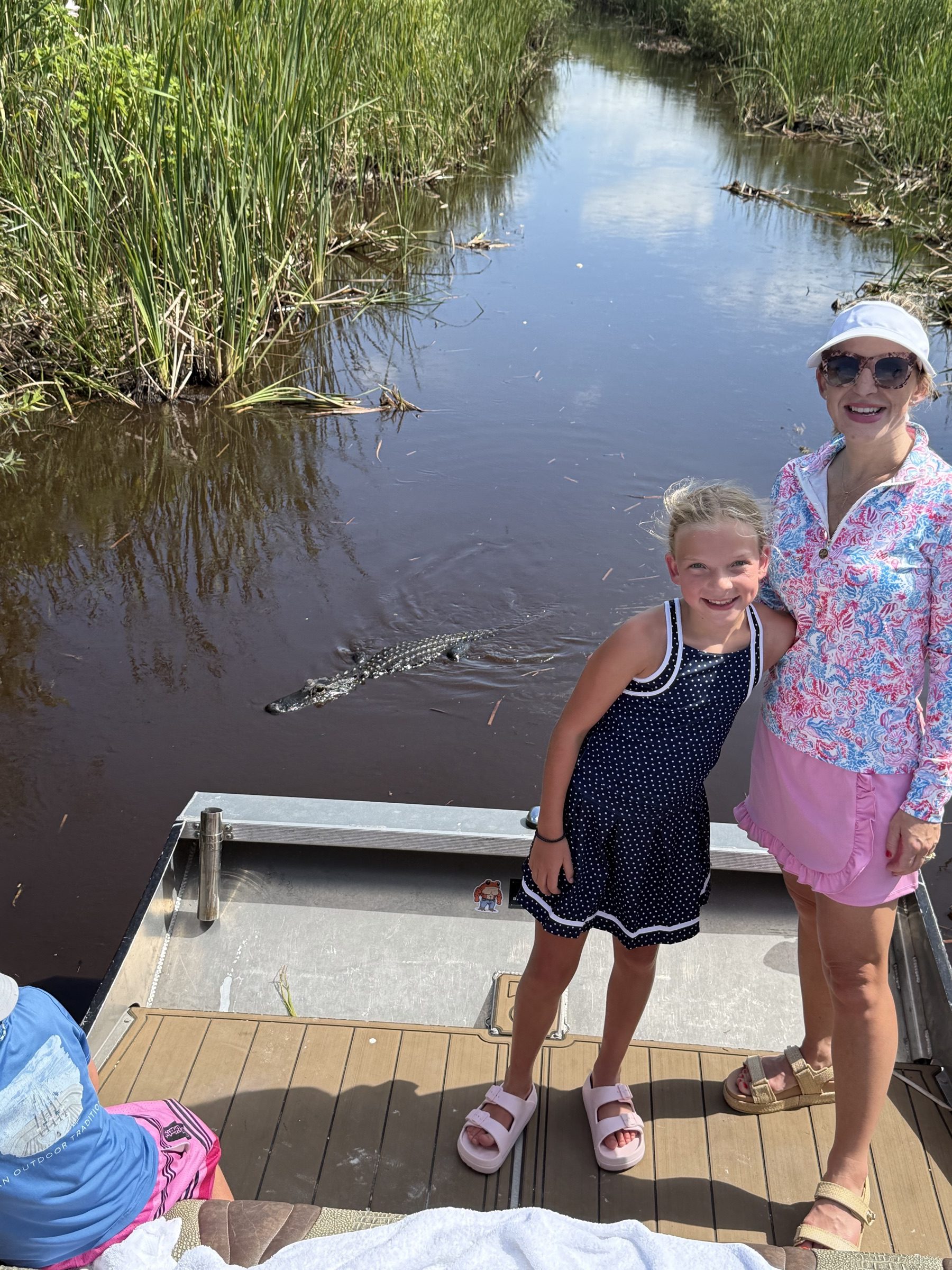 Guests watching an alligator glide past the dock before an Everglades airboat ride near North Lauderdale