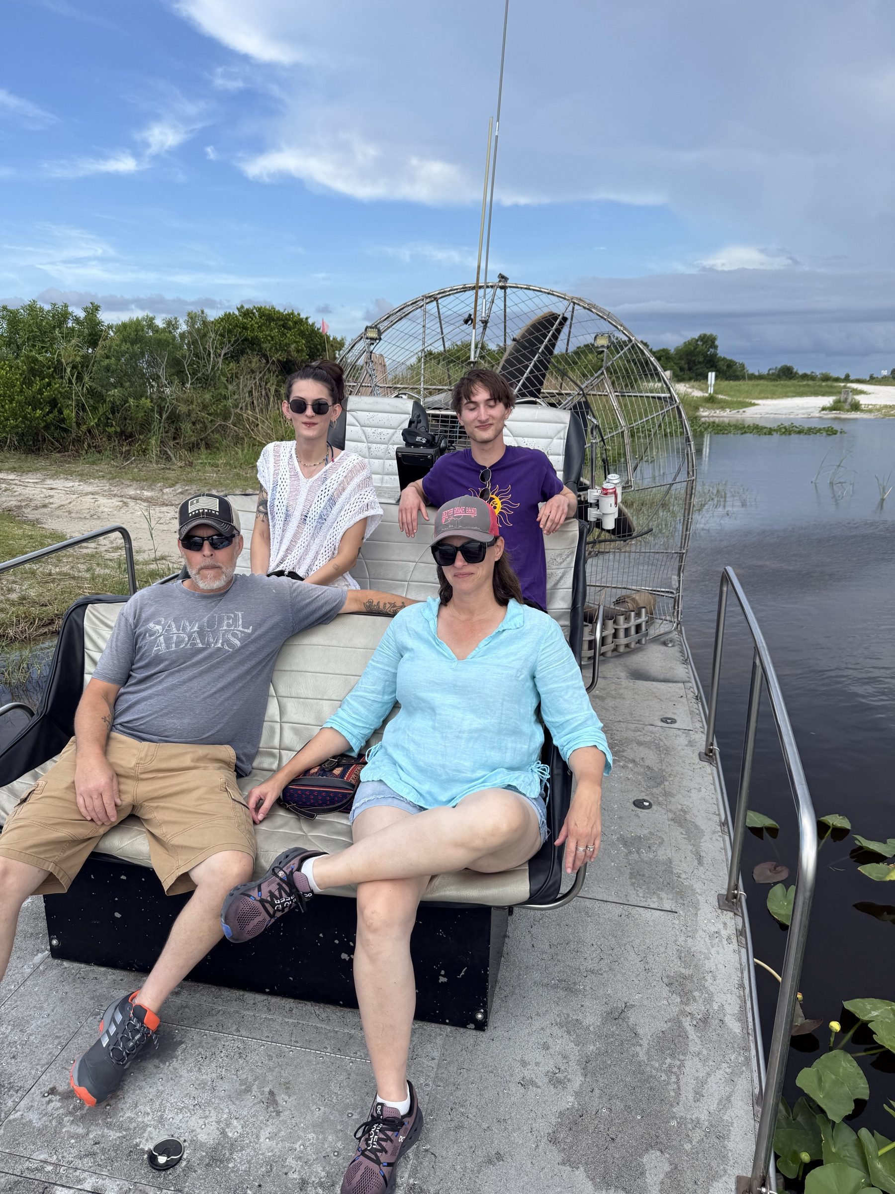 Four guests on an Aces Airboat Tours private Everglades airboat charter under a dramatic sky
