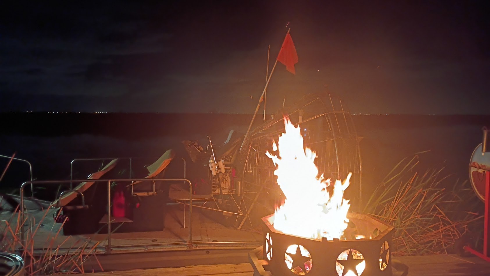 A campfire glowing on the airboat dock at night in the Everglades